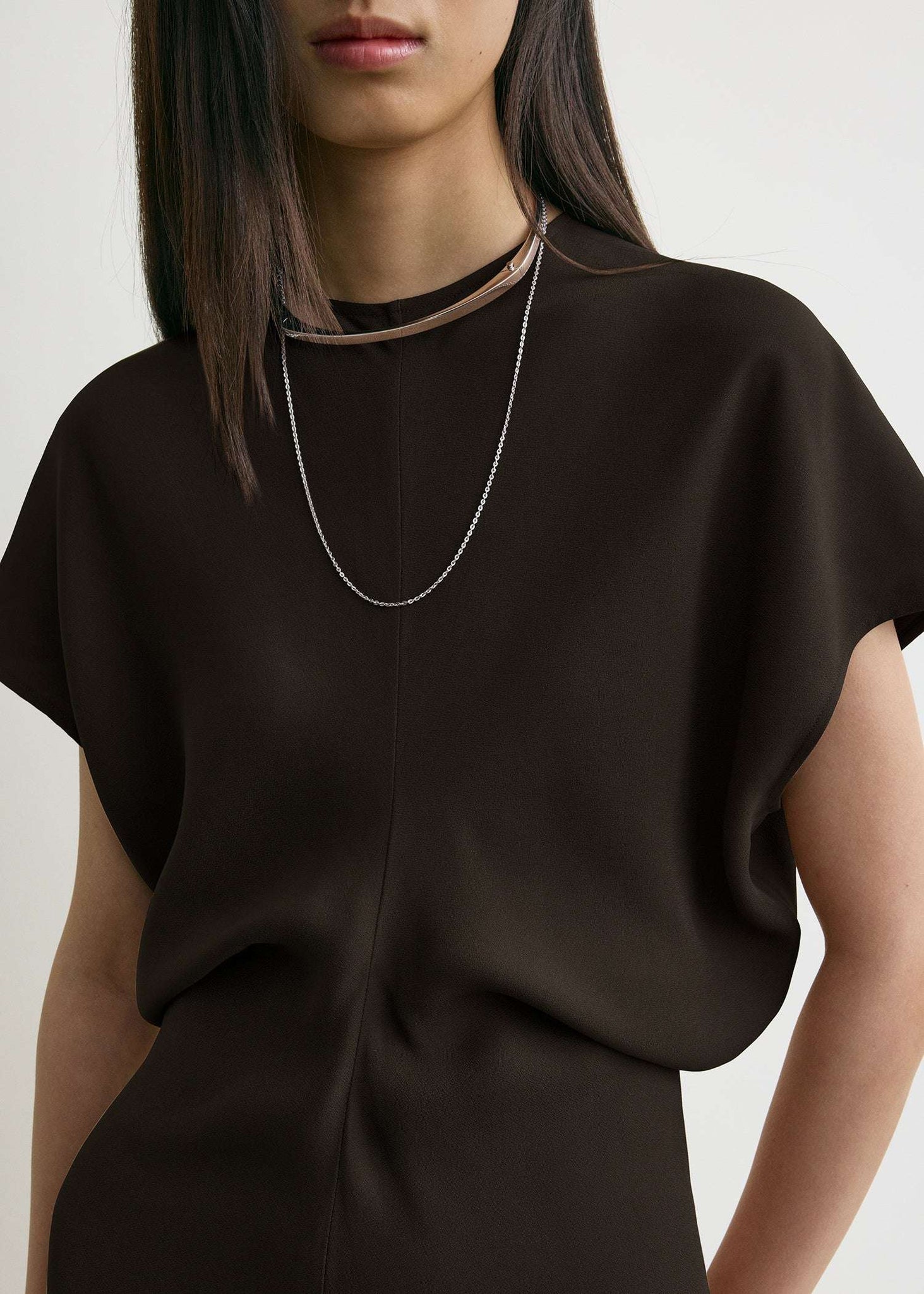 Model wearing the TOTEME Slouch Waist Dress in Bark, styled with a clutch and heels.