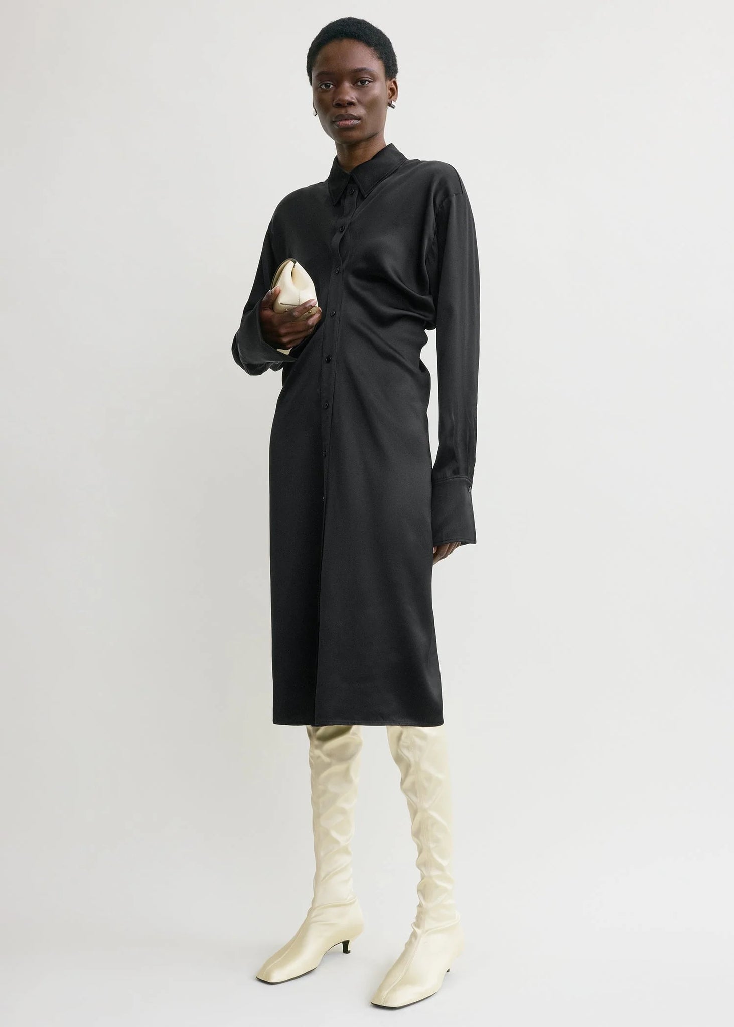 Full view of the Slouch Shirtdress in Black by TOTEME styled with white accessories for a modern contrast look.