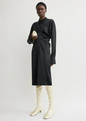 Full view of the Slouch Shirtdress in Black by TOTEME styled with white accessories for a modern contrast look.