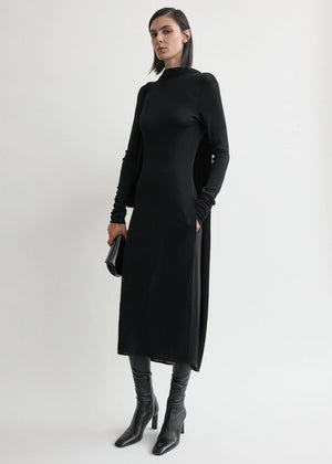Model wearing Cocoon Cape Dress in Black by TOTEME, highlighting its relaxed cocoon shape and slightly dipped hem.