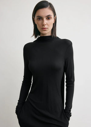 Back view of the Cocoon Cape Dress in Black by TOTEME, illustrating the stunning cape-like panels and low-cut back.
