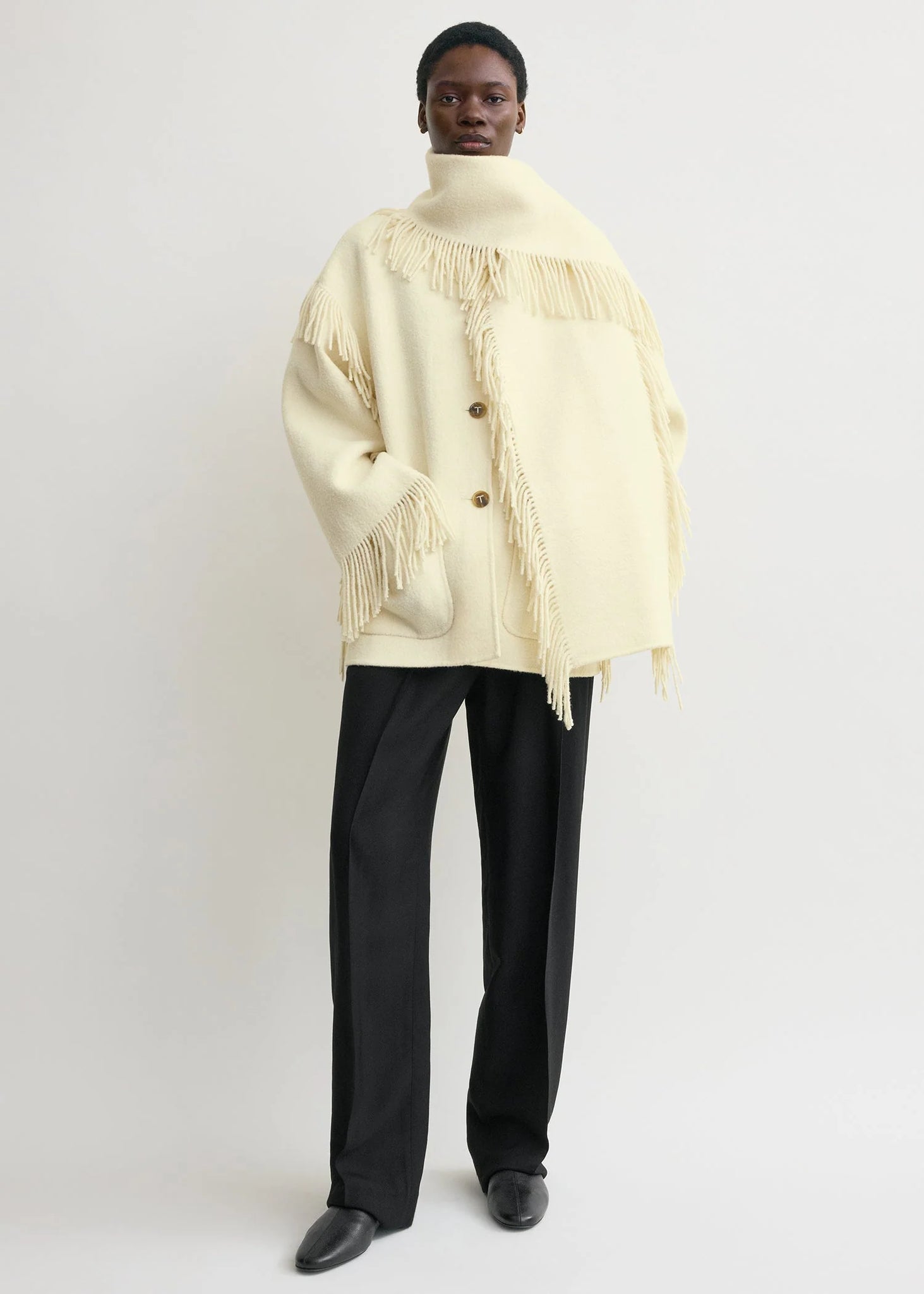 Close-up of the Fringed Scarf Jacket in Winter White, highlighting the unique fringe details and luxurious feel.