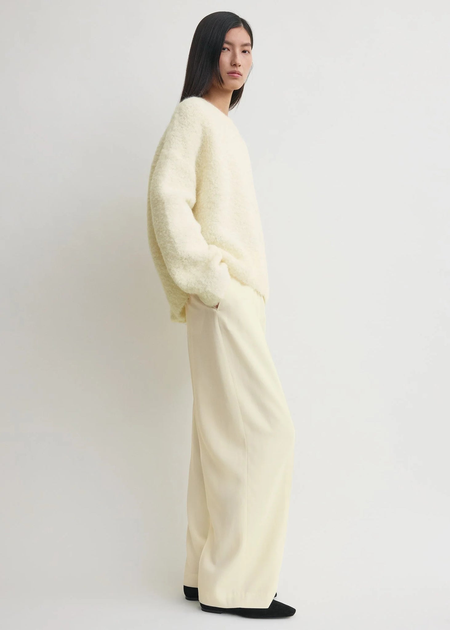 Model wearing the Boxy Boucle Knit in Milk, styled with white trousers for a chic monochromatic look.