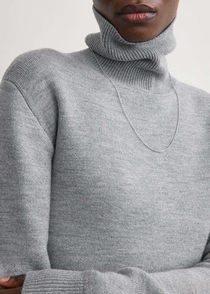 Back view of the High-neck Double Knit Sweater in Pale Grey Melange, emphasizing the long, sculptural hem.