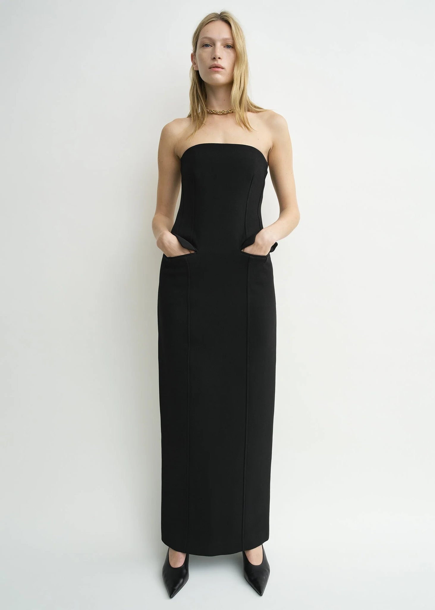 Stylish view of the TOTEME Strapless Pocket Dress in Black highlighting the back zipper and slit detail.