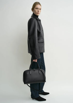 Side view of the Grained Leather Jacket in Black by TOTEME highlighting its effortless fit and stylish design.