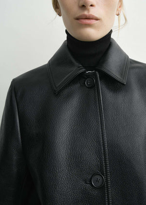 Lifestyle image of a model wearing the Grained Leather Jacket in Black by TOTEME, promoting everyday wear.