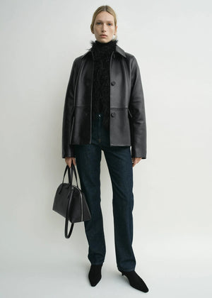Close-up detail of the button placket on TOTEME's Grained Leather Jacket in Black, featuring a soft satin interior.