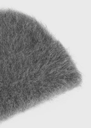 Alpaca Beanie Hat in Dark Grey Melange laid flat on a surface, emphasizing its rich color and luxurious feel made from alpaca wool by TOTEME.