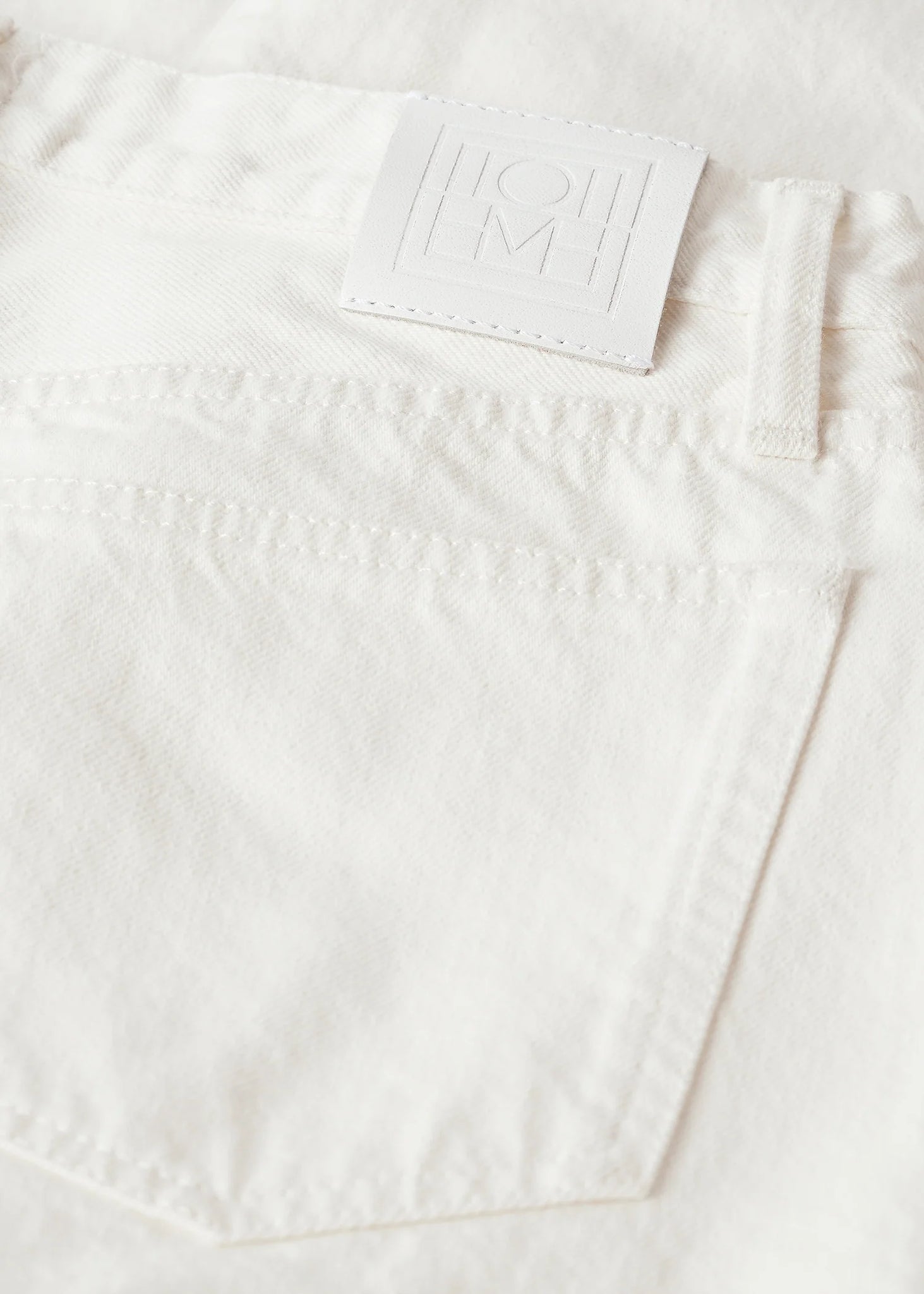 A model wearing the Twisted Seam Full Length Jean in Off-white, demonstrating its movement and relaxed taper.