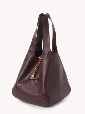 Close-up of the Small Chloé Balloon Bag in Grenat highlighting the gold-tone toggle clasp and chain.